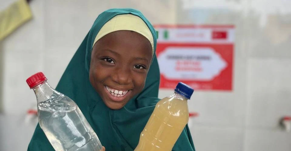 'Su Kuyusu Bağışı Nasıl Yapılır?' başlığı için çeşmeli bir su kuyusu önünde temiz ve kirli su şişesi tutan Afrikalı kız