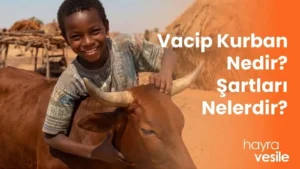 Bir kurbanlık ineğe sarılarak gülümseyen Afrikalı bir çocuk ve yanında "Vacip Kurbanı Nedir? Şartları Nelerdir?" başlığı.