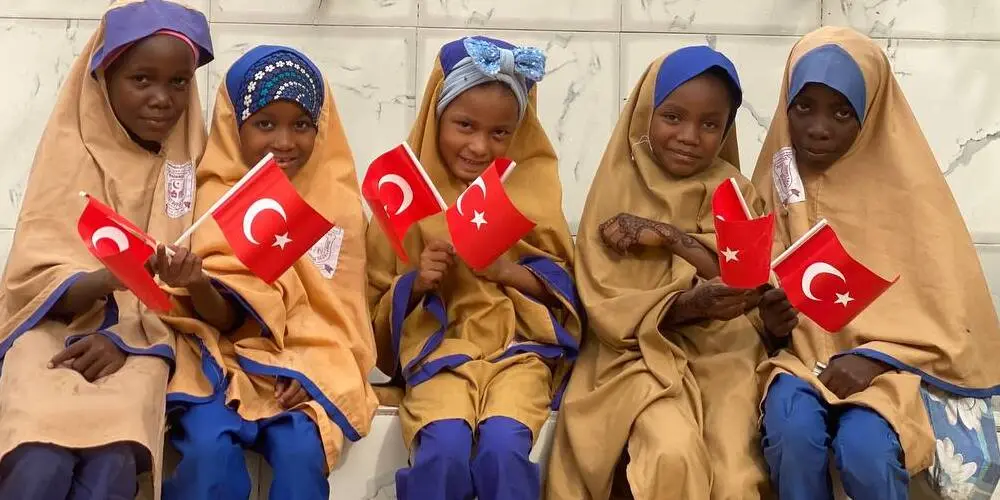 'Fitre Nedir? Neden Verilir, Nasıl Hesaplanır?' başlığı için Afrikalı kızların Türk bayrağıyla poz vermesi